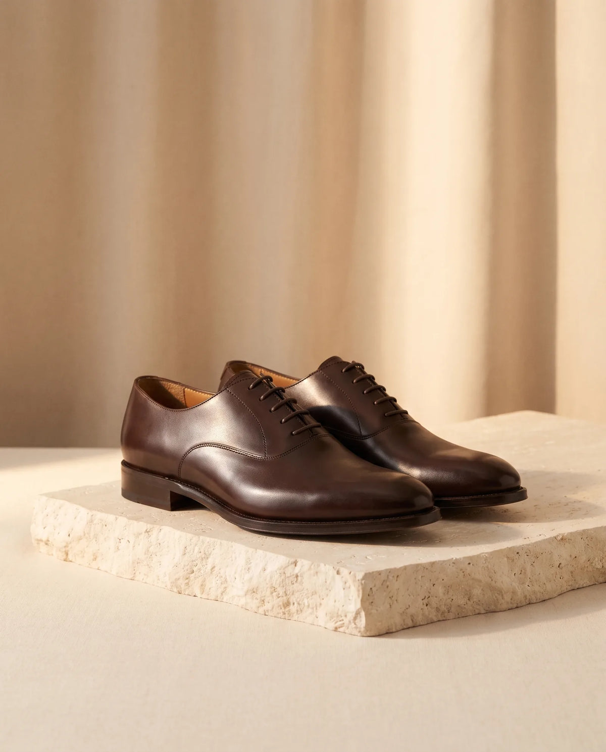 Dark brown leather Oxford dress shoes on stone plinth